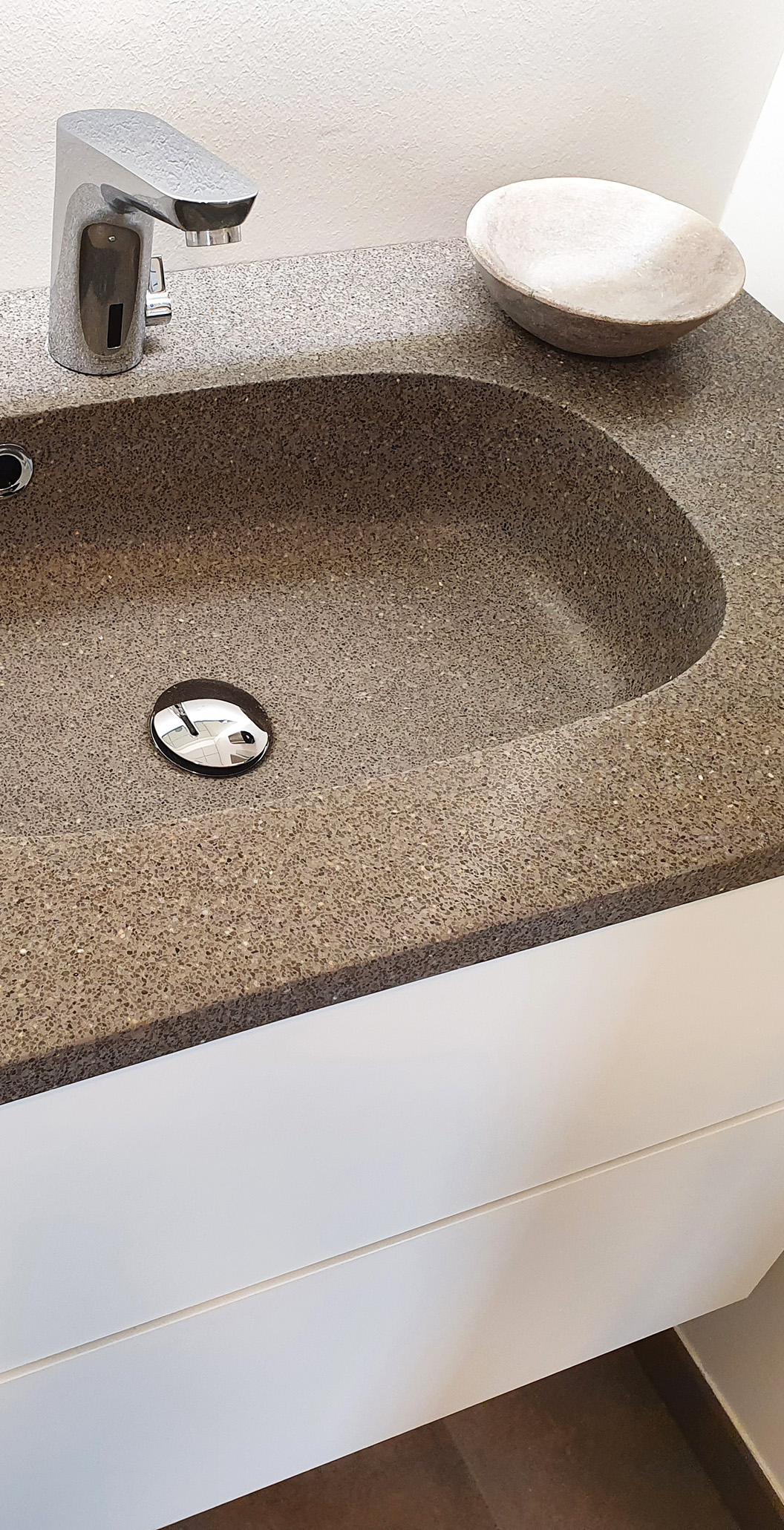 Terrazzovask i natursten i anvendelse på privat badeværelse ovenpå møbel med hvid skuffer og med en keramisk sæbeskål ovenpå leveret af ekspert i materialer til gulve Stonewalk