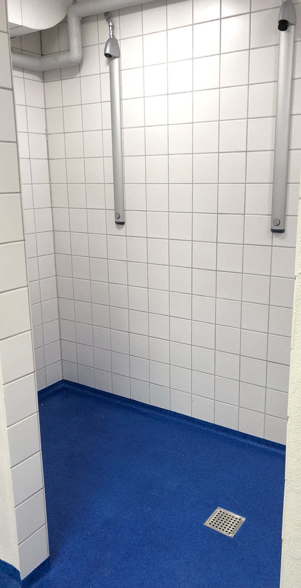 Blå vådrumsgulv, skridsikre gulve og fugefri gulve i bad- og omklædningsrum med hvide klinker på væggene i Engesvanghallen leveret af ekspert i materialer til gulve Stonewalk